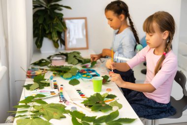 İki liseli kız yaprak çizer, kızlar sonbahar yapraklarını boyarlar