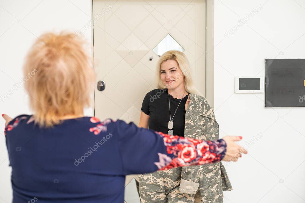 Soldier woman returning home to her family, embracing his mother, close up