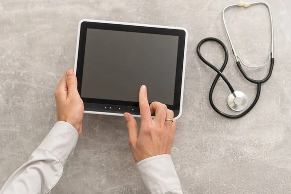 Top view of doctor hands with tablet computer. Cardiac examination in hospital. Therapist sitting at desk with stethoscope. Examination and consultation in clinic — Stock Photo, Image