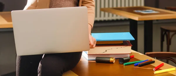 Mãos close-up de mulher de negócios trabalhando no laptop e fazendo avisos em seu caderno sobre mesa de madeira — Fotografia de Stock