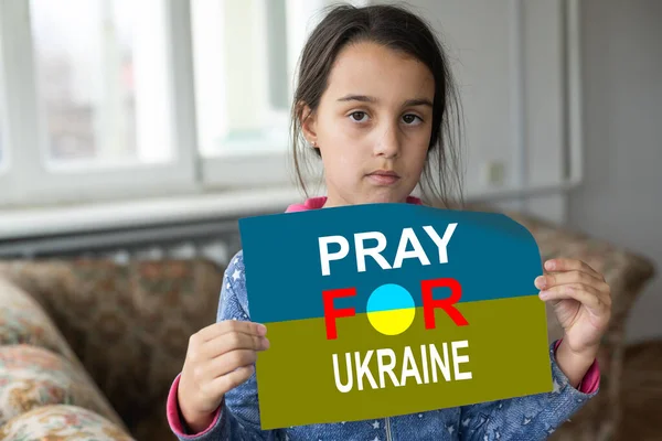 Грустная девочка, покрытая флагом Украины. Концепция положения с украинским народом в войне с Россией — стоковое фото