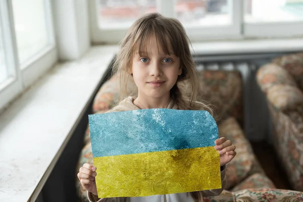 Trauriges kleines Mädchen mit Ukraine-Fahne bedeckt. Konzept, mit der ukrainischen Nation im Krieg gegen Russland zu stehen — Stockfoto