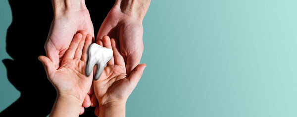 Childs hands holding big tooth and toothbrush on pink backgroubd. Healty care teeth concept. Top view, flat lay. Copy space for your text.