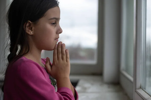 Маленька дівчинка молиться на білому столі вранці. Маленька дівчинка молиться, руки складені в молитовній концепції за віру, духовність і релігію . — стокове фото