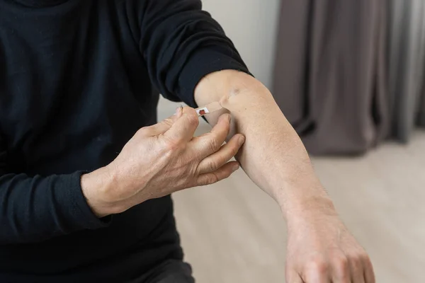 Närbild som en äldre man placerar ett stort fyrkantigt bandage på handen — Stockfoto