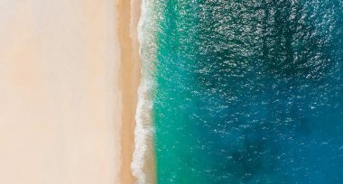 Güzel bir turkuaz denizin kıyısındaki temiz, beyaz kumlu plajın yukarıdan aşağıya manzarası.