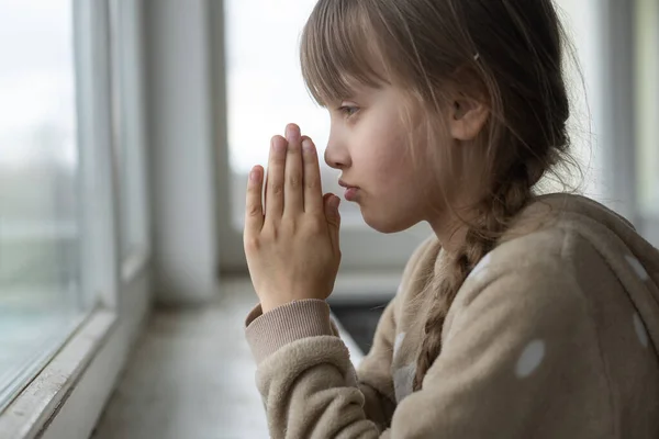 Маленька дівчинка молиться біля вікна . — стокове фото