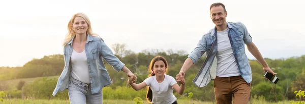 Familia feliz: madre padre e hija en la naturaleza al atardecer — Foto de Stock