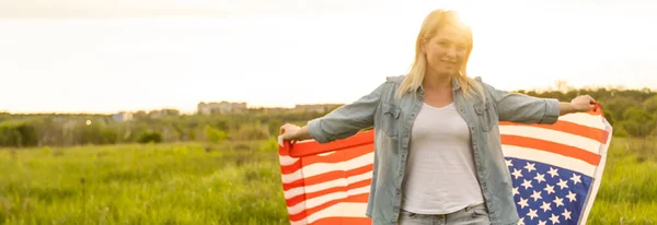 Femme tenant le drapeau américain à l'extérieur sur une prairie. 4 juillet - Jour de l'indépendance. — Photo