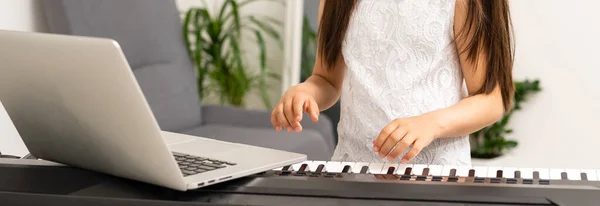 Mała dziewczynka uczy się grać na syntezatorze. nauka gry na instrumentach muzycznych. — Zdjęcie stockowe
