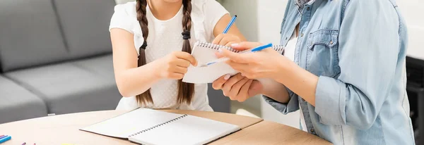 Mãe e filha bonita e feliz fazer um cartão para o dia das mães sentadas juntas à mesa com papel e lápis — Fotografia de Stock