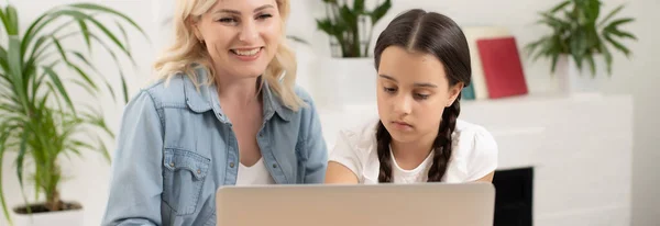 Schöne junge Frau und ihre kleine süße Tochter benutzen zu Hause Laptop. Die gemeinsame Zeit genießen. — Stockfoto