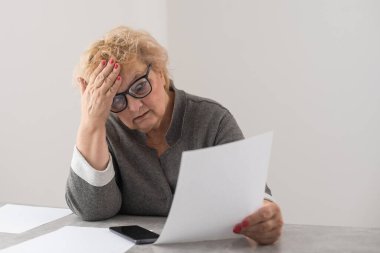 Emekli kadın ev faturalarını hesaplıyor.