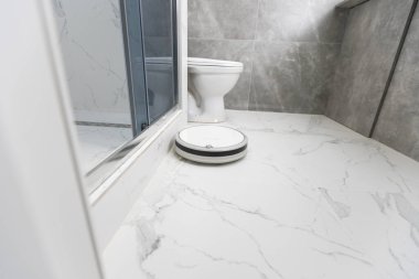 Banyoda beyaz robot elektrikli süpürge.
