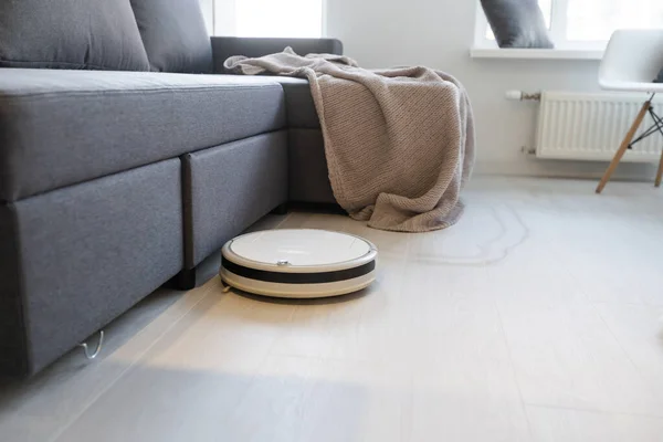 Smart House. Aspirapolvere robot corre sul pavimento in legno in un soggiorno — Foto Stock