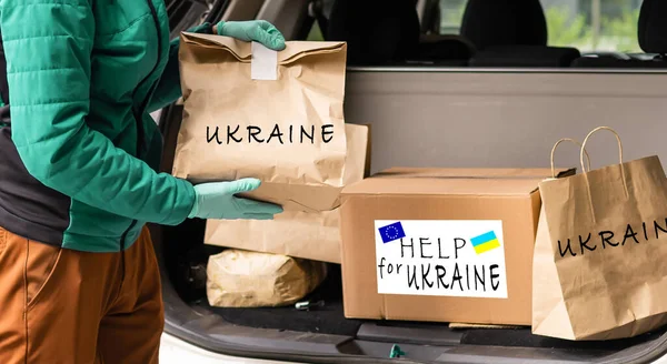 Close up of volunteer cyrrying box with Humanitarian aid for Ukrainian refugees in street — Stock Photo, Image