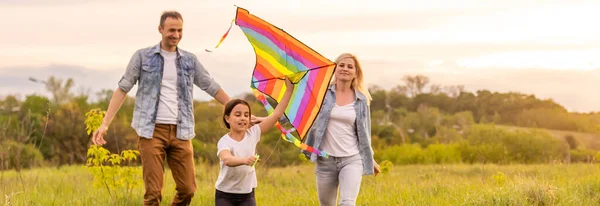 Счастливая семья отец, мать и ребенок дочь запустить воздушного змея на природе на закате — стоковое фото