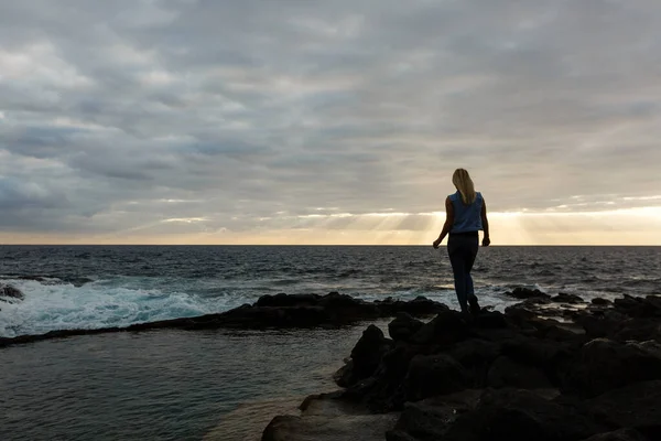 Les femmes sur les roches volcaniques et l'océan bleu avec des vagues, de la mousse blanche et des roches volcaniques. Îles Canaries. La magnifique côte de l'océan Atlantique — Photo