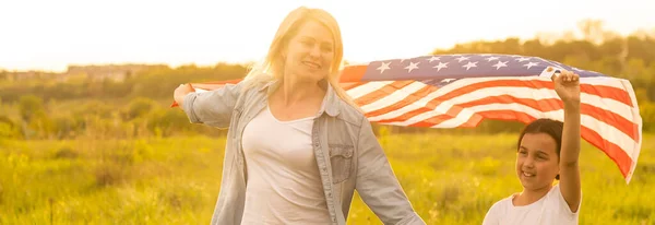 아름다운 들판에 미국 국기를 단 어머니와 딸 — 스톡 사진