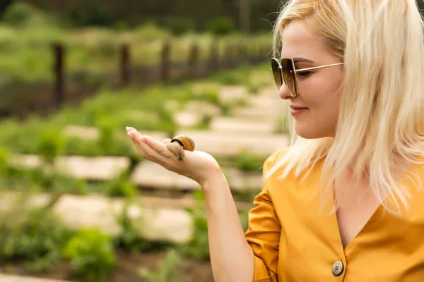 Gros plan des escargots sur les femmes main dans la serre d'une ferme pour la culture des escargots. — Photo