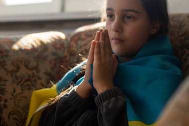 Ukrayna bayrağıyla kaplı küçük bir kız. Rusya ile savaşta Ukrayna ulusuyla birlikte olma kavramı.