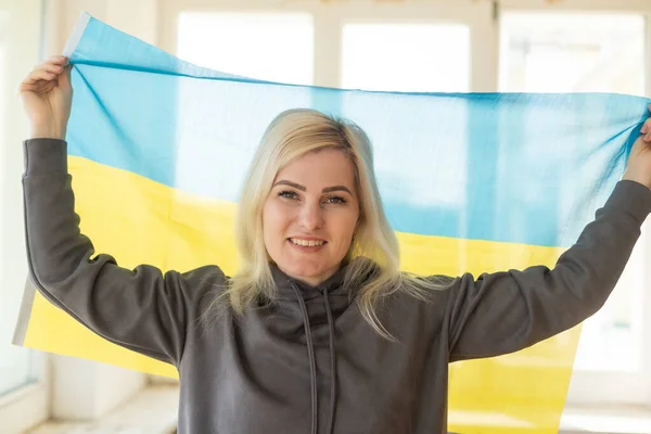 Flüchtlingsfrau mit ukrainischer Flagge. Patriotismus, Kampf, Hoffnung. Krieg in der Ukraine. Freiheit für die Ukraine. Es gibt keinen Krieg. — Stockfoto