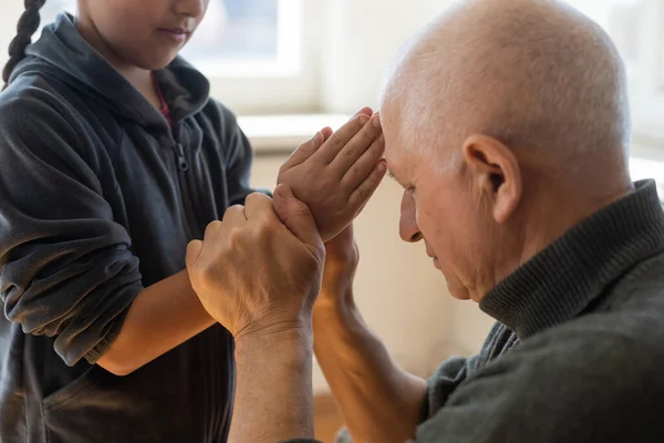 Руки дедушки и внучки с молитвой — стоковое фото