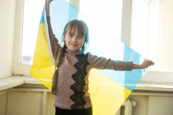 Ein kleines Mädchen mit der gelb-blauen Flagge der Ukraine, stoppt den Krieg, protestiert und Patriot, hofft auf Frieden. — Stockfoto