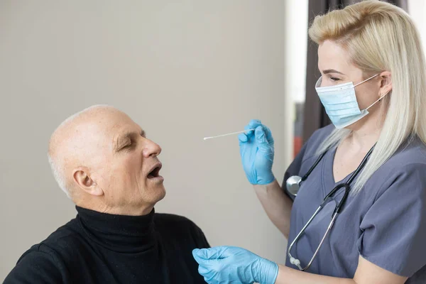 Médecin utilisant le test d'écouvillonnage du nez coronavirus COVID-19 avec un homme âgé âgé à l'hôpital. Examen médical pour COVID-19 à l'hôpital. — Photo