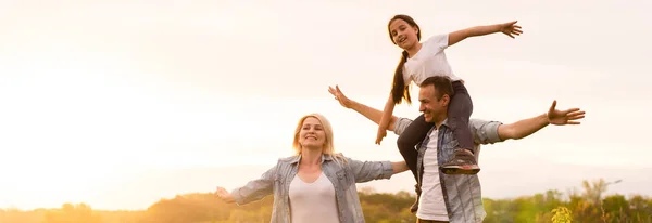 Familia feliz en la luz de la tarde del parque. Las luces de un sol. Mamá, papá y bebé caminan felices al atardecer. El concepto de una familia feliz — Foto de Stock