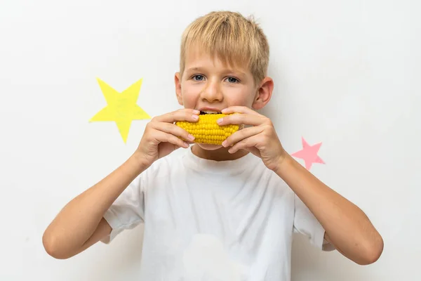 하얀 배경 이 있는 옥수수 덩어리를 먹고 있는 어린이의 사진 — 스톡 사진