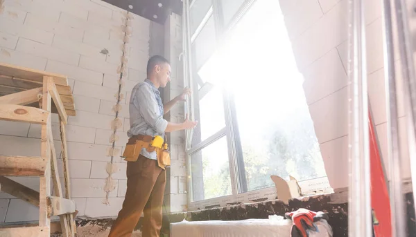 Чоловік працівник встановлює вікно в квартирі, крупним планом — стокове фото