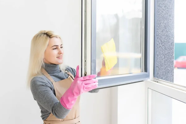 Young woman in apron cleaning windows. Cleaning service. Maid cleaning at home — Stock Photo, Image