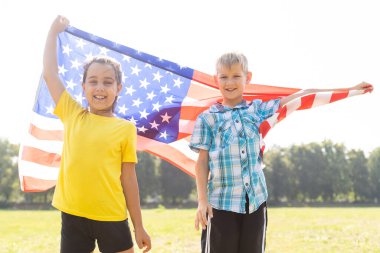 Çocuklar açık havada Amerikan bayrağıyla oturuyorlar..