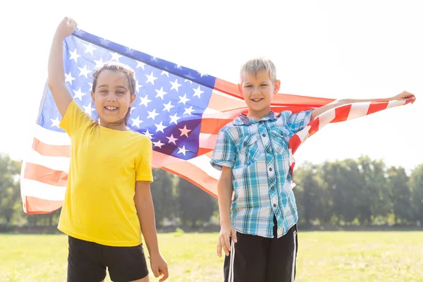 Dzieci siedzą z amerykańską flagą na zewnątrz. — Zdjęcie stockowe
