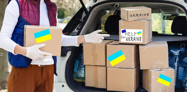 Чоловік тримає коробку з гуманітарною допомогою Україні — стокове фото