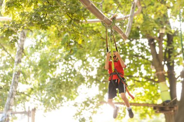 Çocuk tırmanışçı ip köprüde yürüyor,