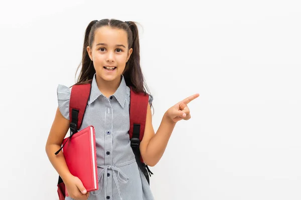 Liten skolflicka visar på vit bakgrund — Stockfoto