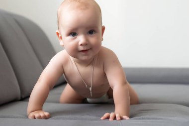 Gri bir kanepede gülümseyen şirin bir bebek.