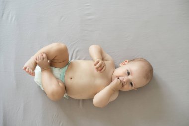 Odasındaki yatakta emekleyen bir bebeğin portresi.