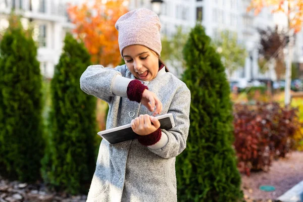 Gelukkig klein meisje holding tablet pc buiten — Stockfoto