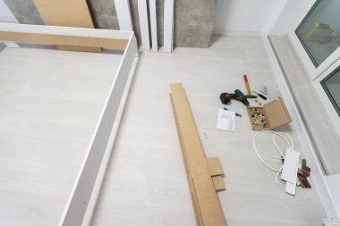 Etek tahtalarının kurulumu, ana yapıştırıcılar duvarın dış köşesine zemin silindirleri, eller.