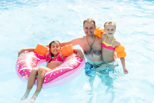Familia feliz jugando en la piscina. Concepto vacaciones de verano — Foto de Stock