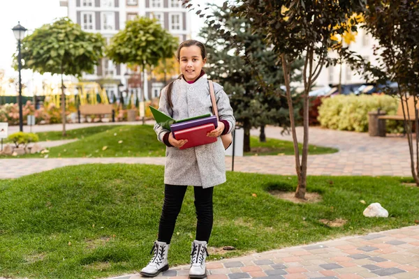 Mooi klein meisje met rugzak lopen in het park klaar terug naar school, vallen buiten, onderwijs concept. — Stockfoto