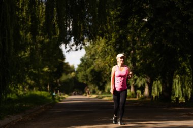 Koşan kadın. Bir parkta spor yaparken koşan bir bayan koşucu..
