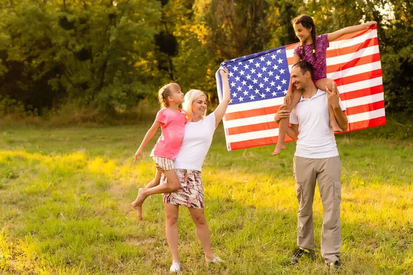 Familia feliz con la bandera de Estados Unidos al atardecer al aire libre — Foto de Stock