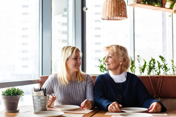 Két boldog nő beszélget a kávézóban. Egy idős nő és a felnőtt lánya kávéznak a kávézóban. Anyák napja. — Stock Fotó