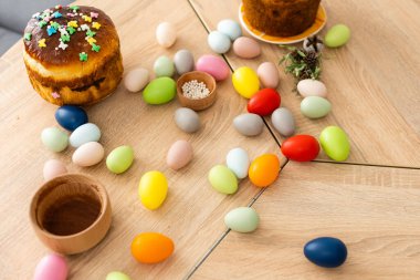 Paskalya pastası, renkli yumurtalar ve çiçekler ön planda.