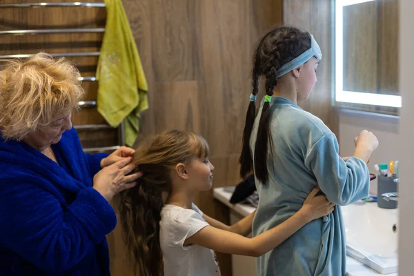 Oma kämmt ihren Enkelinnen sorgfältig die Haare — Stockfoto