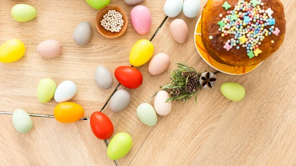 Easter cake with sprinkles, painted eggs and flowers on wooden table, flat lay. Space for text — Foto Stock